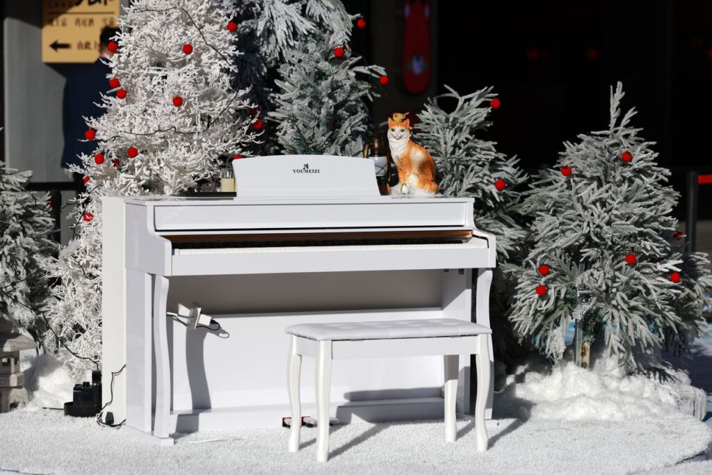 A white piano in a snowy setting, surrounded by festive frosted trees with red baubles.
